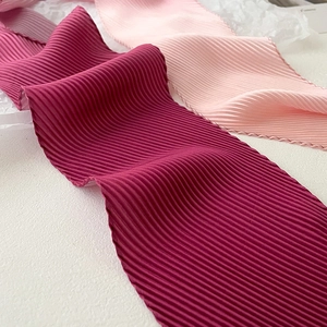 Detail of pleated silk texture scarves in burgundy and pink with fine accordion folds