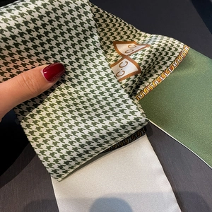 Macro detail of houndstooth twilly scarf with green chain patterns and silk texture