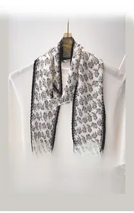 Détail d'un foulard en soie plissé crème avec motif paisley et liseré noir contrasté