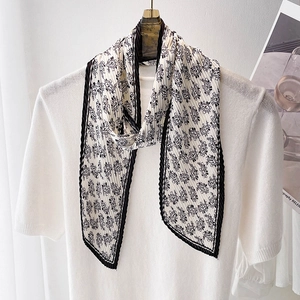 Détail d'un foulard plissé noir et blanc avec motif cachemire sur haut blanc