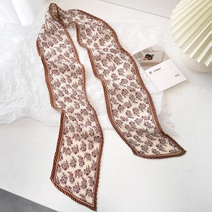 Détail d'une écharpe plissée en soie crème avec des motifs paisley marron élégants