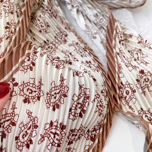 Gros plan sur le tissu plissé crème d'un foulard avec des motifs cachemire bruns