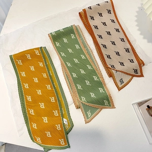 Detail of pleated silk scarf featuring repeating letter R patterns and micro-fold texture