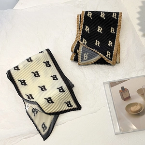 Detailed view of pleated silk scarves in black and white with letter R print design