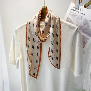 Detail of pleated silk scarf with letter R print and orange trim on white knit top