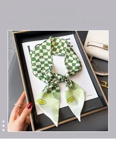 Close-up of green checkerboard silk scarf featuring smiley face and NICE lettering detail