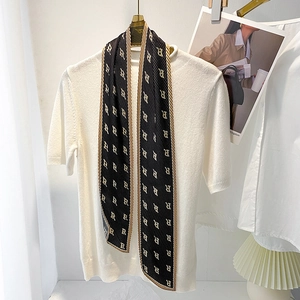Detail of black pleated skinny scarf with golden R letter prints and striped border