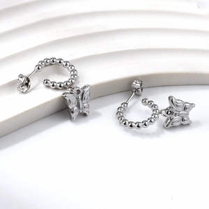 Detailed macro view of butterfly drop earrings on white wave texture display stand