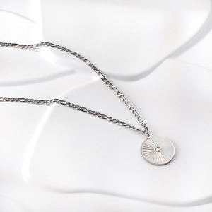 Macro shot of silver Figaro chain necklace with a sunburst and white shell pendant