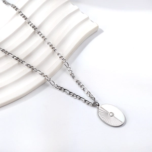Macro detail of Figaro chain and 18K gold plated sunburst oval pendant with zircon