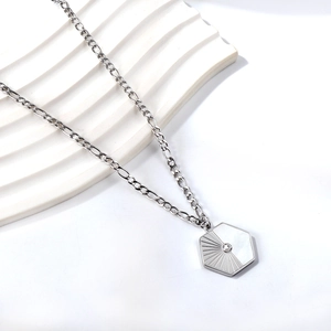 Detailed macro view of a silver hexagonal pendant with white shell and zircon stone
