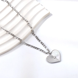 Macro shot of silver heart pendant with white seashell inlay and sparkling zircon detail