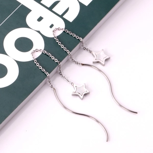 Detailed view of long star chain earrings with white inlay on a green book