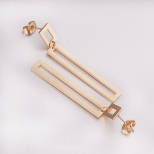 Detailed view of long geometric gold earrings with rectangular hollow pendants on white background