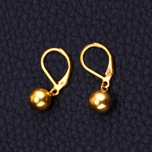 Gros plan de boucles d'oreilles dorées avec perles sphériques sur cuir bleu foncé