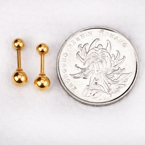 Gros plan de boucles d'oreilles boules dorées avec pièce pour référence de taille
