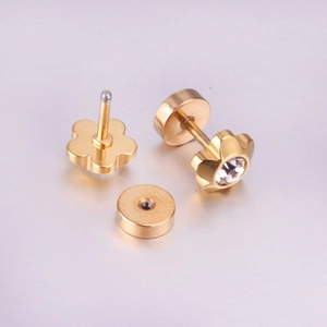 Detail of golden flower cartilage stud earrings with central zircon and secure screw back