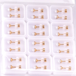 Set of 12 pairs of minimalist white pearl stud earrings with gold pins in a grid tray