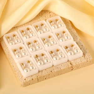 12-pair set of elegant white pearl earrings with gold pins on natural stone base