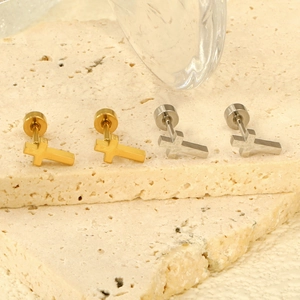 Boucles d'oreilles croix minimalistes en or et argent sur fond de pierre naturelle