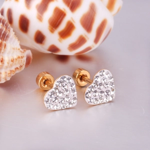 Close-up of gold heart stud earrings with white rhinestones and decorative shells