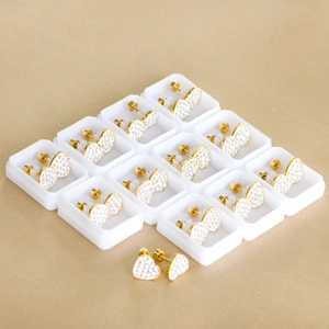 Golden heart stud earrings with crystal pave and secure screw backs on textured background