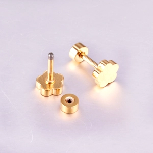 Détail macro de boucles d'oreilles fleurs dorées avec fermoir à vis et finition polie