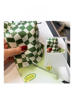Macro detail of silk-like green checkered scarf with yellow smiley faces and NICE text
