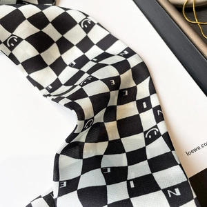 Detail of checkered silk scarf with smile patterns and smooth fabric texture close-up