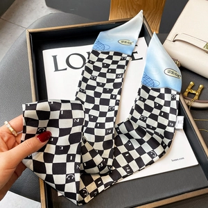 Detail of checkered silk scarf with smiley face pattern and blue accent on luxury bag