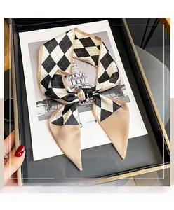 Close-up of diamond pattern silk scarf tied in a bow inside an elegant gift box
