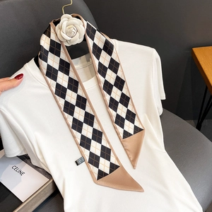 Detail view of a satin twilly scarf with black and white diamond pattern on a white top