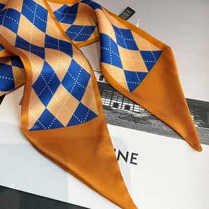 Detailed close-up of diamond pattern silk twilly scarf in orange and navy blue colors