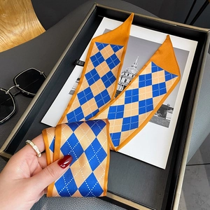 Detailed view of orange and royal blue geometric diamond print silk twilly scarf texture