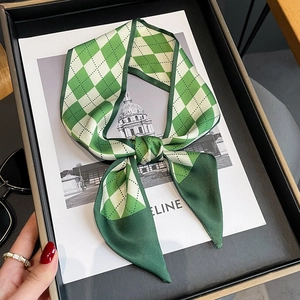 Elegant green diamond pattern silk scarf tied in a bow on a luxury display card