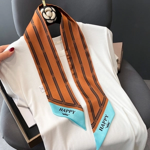 Detail of striped narrow silk scarf with blue tip and crown print on white t-shirt