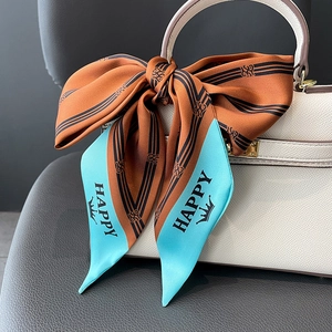 Elegant orange striped silk twilly scarf tied in a bow on white leather bag handle