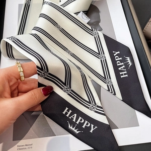 Close-up of black and white striped twilly scarf with crown motif and gold ring accessory