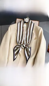Détail d'une écharpe en soie rayée noir et blanc avec des cœurs dorés sur un blazer