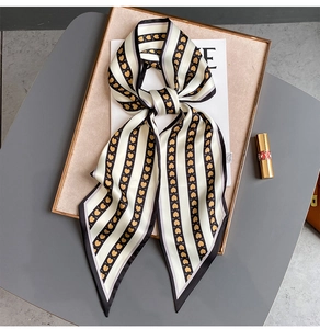 Détail d'un foulard étroit en soie beige à motifs cœurs et rayures sur un plateau
