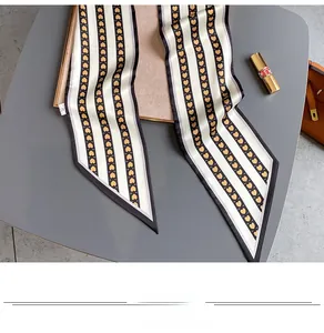 Détail d'un foulard étroit en soie avec rayures noires et cœurs jaunes sur crème
