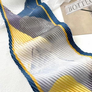 Détail d'un foulard en soie plissé avec blocs de couleurs abstraits et plis accordéon
