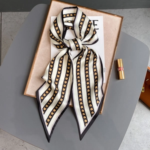 Détail d'un foulard twilly à cœurs noué en nœud sur un magazine avec rouge à lèvres