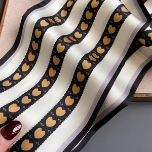 Vue détaillée du foulard en soie à motif cœur montrant la texture fine et l'éclat
