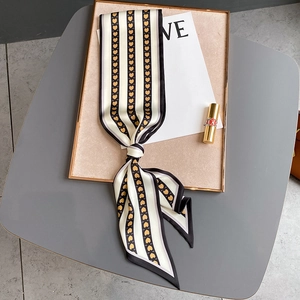 Détail d'un foulard en soie à motif cœurs et rayures, posé avec des accessoires beauté