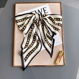 Détail d'un foulard en soie rayé avec imprimé cœur doré et design élégant en nœud