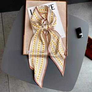 Détail du foulard twilly en soie avec motifs de cœurs orange et texture lisse chic