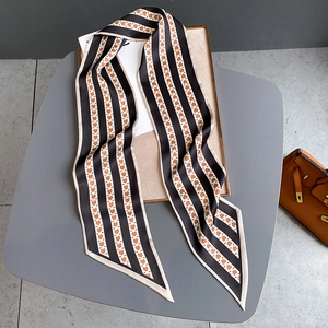 Détail d'un twilly à rayures et motifs cœurs sur un plateau avec un sac à main chic