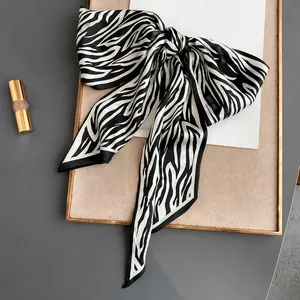 Detalle de un pañuelo de seda con estampado de cebra atado en lazo sobre bandeja de madera