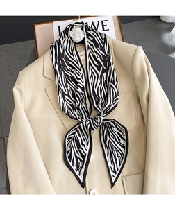 Detalle de un pañuelo Twilly con estampado de cebra anudado a un blazer beige elegante